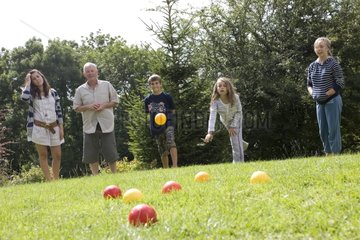 Familie spielt Boule auf Rasen mit farbigen Plastikkugeln UK
