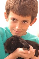 Enfant portant un lapin bélier noir