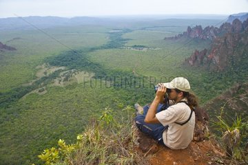 Tourists sitting on cliff Chapada dos Guimaraes Brazil
