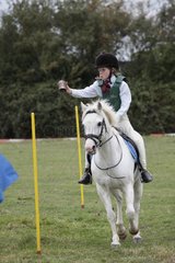 Girl riding white pony in tin can race gymkhana UK