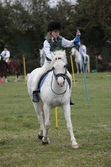 Girl riding white pony in flag race gymkhana UK