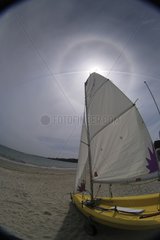 Sailboat in front of the Sun and its halo of 22 Â° radius