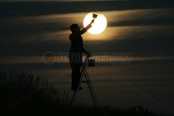 Woman giving the impression of painting the Moon France