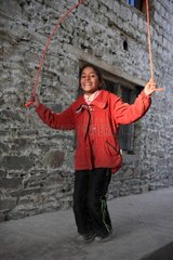 Girl playing jump rope outside a house India