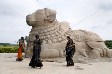 Women in saris in front of the statue of the god Lepakshi Nandi India