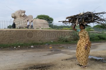 Woman walking in front of the Nandi statue of the god in India