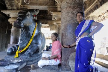 Women in saris in front of the statue of the god Nandi in Mysore India