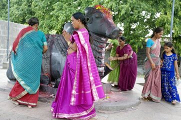Women in saris around a statue of the god Nandi in India