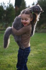 Child taking a cat on her shoulders