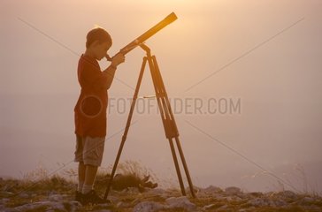 Child observing the sky through a telescope