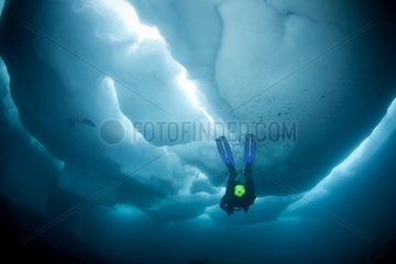 Scuba diver under and between ice formations Lake Sassolo