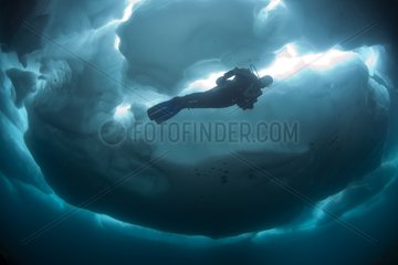Scuba diver under and between ice formations Lake Sassolo