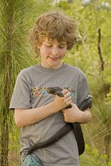 Boy holding a Black pine snake Mississippi USA