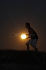 Person giving the impression of playing basket with the Moon