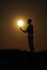 Person giving the impression of playing basket with the Moon