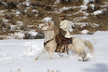 Cowboy on his quarter horse in the snow Wyoming USA