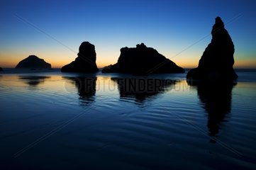 Reflection of old sea stacks at sunset on the Bandon beach