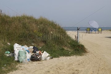 Table and chairs under a beach umbrella and garbage Normandy
