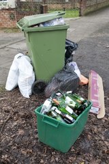 Green wheelie bin overflowing with domestic rubbish UK
