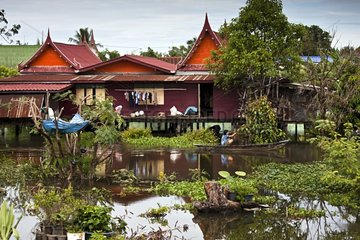 House on pilotis and woman in a boat in Thailand