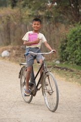 Schoolboy back from school by bicycle in Burma