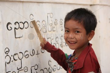 Child deciphering inscriptions on a wall Burma