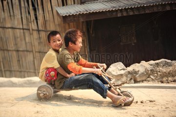 Children on a bicycle built house with pieces of wood Burma