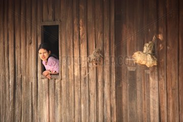 Young woman at her window in a village in Burma
