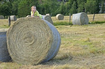 Young boy lying on a bale of hay France