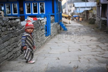Boy in traditional clothing in an alley Chame Nepal