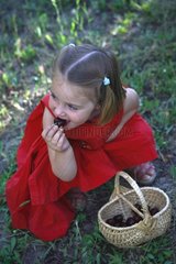 Girl eating cherries in a small basket France