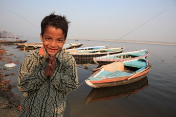 Portrait of boy saluting and boats Varanasi India