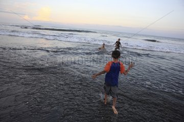 Boys bathing on a black sand beach Bali