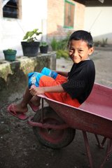 Boy sitting in a wheelbarrow Bukittinggi Sumatra Indonesia