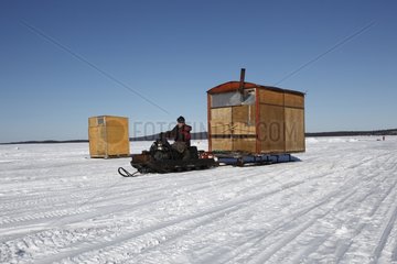 Wooden cabins on sledges moving with the ski-doo White Sea