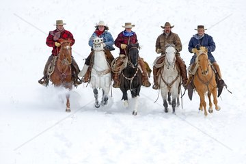 Cowboys riding in the snow in winter Wyoming US