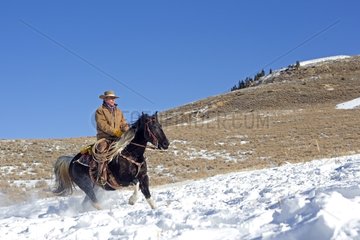 Cowboy riding in the snow in winter Wyoming US