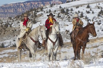 Cowboys riding in the snow in winter Wyoming US