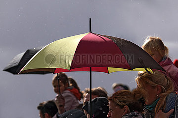 Hoppegarten  Deutschland  Regenschirm in den deutschen Nationalfarben vor grauem Himmel