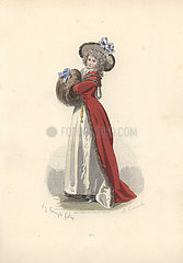 Woman in wig and bonnet  long crimson coat over white skirts  with both hands in a huge fur muff.