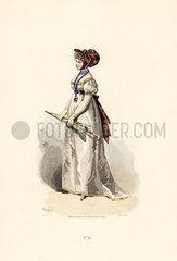 Woman in white dress with straw-coloured trim and garnet belt.