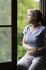 Thoughtful woman sitting on window