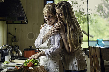Daughter embracing her mother in kitchen