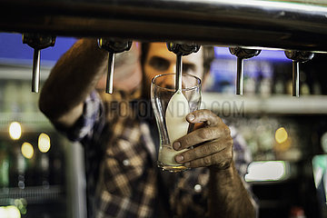 Close-up of man drawing beer from tap