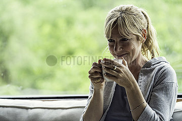 Mature woman having coffee at home
