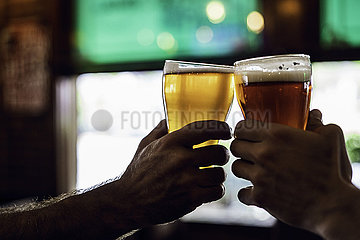 Hands toasting beer glasses