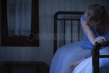 Worried woman sitting on bed
