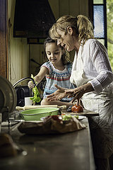 Mature woman teaching her granddaughter in kitchen