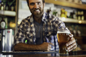 Man holding beer glass at counter