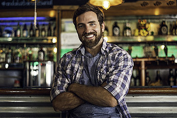 Portrait of smiling man leaning against bar counter